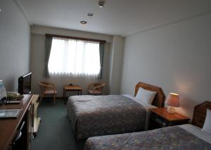 a hotel room with two beds and a television at Hotel Sentpia in Higashi-murayama