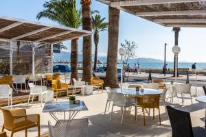 een patio op het strand met tafels en stoelen bij Cabot Romantic- Adults Only in Port de Pollença