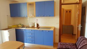 a small kitchen with blue cabinets and a table at Marion apartment in Portorož +11 photos