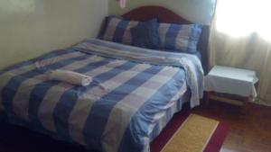a bed with a blue and white striped comforter in a bedroom at Juddy Place in Nairobi