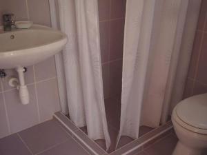 a bathroom with a white shower curtain and a sink at DéeL apartman in Nyíregyháza +23 photos