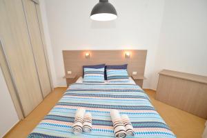 Schlafzimmer mit einem Bett mit gestreifter Decke und Kissen in der Unterkunft Apartments Kriva Ulica in Kotor