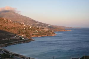 a town on a hill next to the water at Monolithos Villas in Kipri