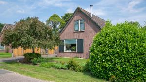 een stenen huis met een raam en een boom bij De Anselier in Ansen