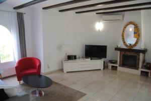 a living room with a red chair and a fireplace at Villa Bozena in Denia