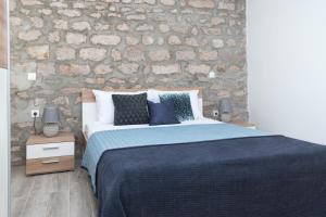 une chambre avec un lit et un mur en pierre dans l'établissement Bounty Apartments, à Šibenik