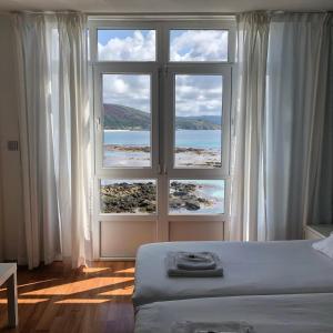 1 dormitorio con ventana grande con vistas al océano en Hotel Mar de Fisterra, en Finisterre