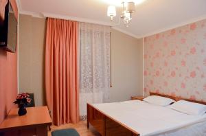 1 dormitorio con 1 cama y una ventana con cortinas de color naranja en Bellis en Tiflis