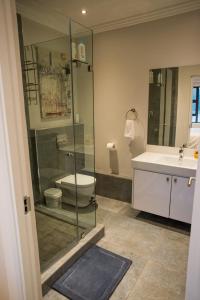 a bathroom with a shower and a toilet and a sink at Stay at The Point - Penthouse Plush Perfection in Durban