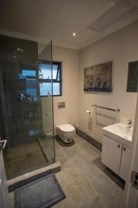 a bathroom with a shower and a toilet and a sink at Stay at The Point - Penthouse Plush Perfection in Durban