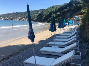 a row of lounge chairs with umbrellas on a beach at Casa Mila apartments & bungalows in Ulcinj