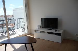 a living room with a flat screen tv on a white cabinet at Le balcon de la Conche in Royan