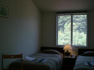 a bedroom with two beds and a large window at Gallery Court Ofa Atu in Kawazu