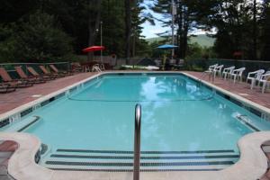 una gran piscina con sillas y mesas en Trekker, Treehouses cabins and lodge rooms, en Lake George