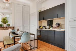 une cuisine avec des armoires noires, une table et des chaises dans l'établissement NOCNOC Grand place Belle vue, à Lille