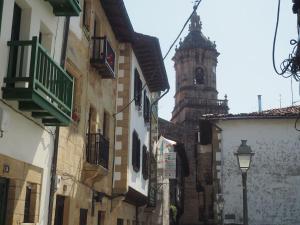 une rue étroite avec une tour d'horloge en arrière-plan dans l'établissement Piso con encanto en la parte vieja., à Fontarrabie