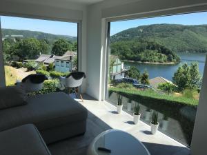 - un salon avec une grande fenêtre donnant sur un lac dans l'établissement Jidajo See Cottage Nationalpark Eifel, à Simmerath