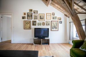 a living room with a tv and framed pictures on the wall at La Maison du Passavant (Gîte à la ferme) in Genappe