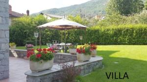 um pátio com flores e um guarda-chuva num quintal em Casa tipica valdostana em Aosta