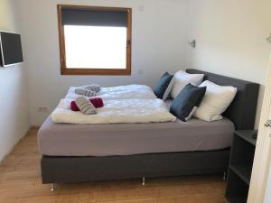 a bedroom with a bed with pillows and a window at Jidajo See Cottage Nationalpark Eifel in Simmerath