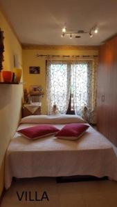 a bedroom with a large bed with red pillows and a window at Casa tipica valdostana in Aosta