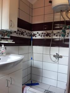 een douche in een badkamer met zwarte en witte tegels bij City Apartment in Visoko