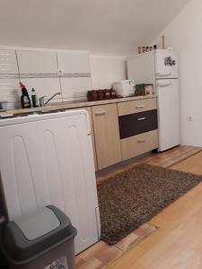 een keuken met een witte koelkast en een vuilnisbak bij City Apartment in Visoko