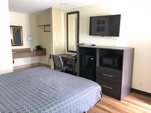 a bedroom with a bed and a desk and a television at Simply Home Inn & Suites - Riverside in Riverside