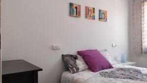 a bedroom with a bed with purple pillows on it at Apartamento Centro , Playa Costa Brava y Barcelona in Malgrat de Mar