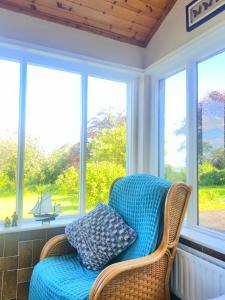 a porch with a wicker chair in front of windows at Leenan View Country House in Portsalon