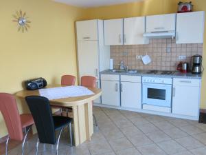 a kitchen with a table and chairs and a kitchen with white cabinets at Schölzke‘s Ferienhaus in Ralswiek