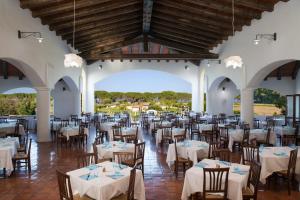 a banquet hall with white tables and chairs at Cala Luas Resort in Cardedu