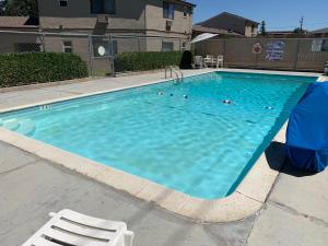 a large blue swimming pool with a white chair and aermottermott at Bestway Inn in Paso Robles