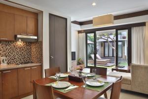 a kitchen and dining room with a wooden table and chairs at Seminyak TownHouse in Legian