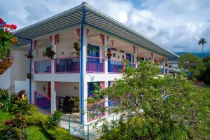 um edifício com varandas e plantas cor-de-rosa e azuis em Hotel El Jardin em Salento