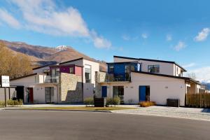a large house with mountains in the background at Apartments on Upton in Wanaka