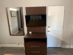een kamer met een televisie en een dressoir met een spiegel bij Bestway Inn in Paso Robles