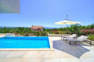 uma piscina com duas cadeiras e um guarda-sol em Villa Silente em Krk