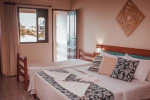 a bedroom with two beds and a window at Pousada Recanto da Pedra in Iriri