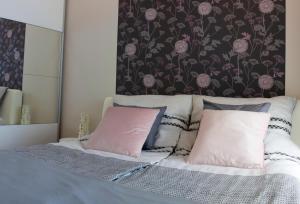 1 dormitorio con 1 cama con almohadas rosas y grises en Center Rev Apartment en Győr