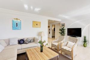 un soggiorno con divano, sedie e TV di Appartement - villa Le Saint Georges avec superbe jardin et vue mer panoramique a Cannes