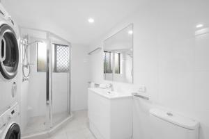 a white bathroom with a sink and a washing machine at Aria Del Mare in Gold Coast