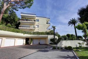 a large white building with a driveway at Appartement - villa Le Saint Georges avec superbe jardin et vue mer panoramique in Cannes
