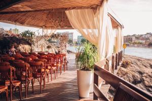 a wooden deck with chairs and a restaurant with the water at Pousada Recanto da Pedra in Iriri