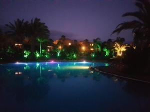een groot zwembad 's nachts met groene verlichting bij Oasis vistamar in Corralejo