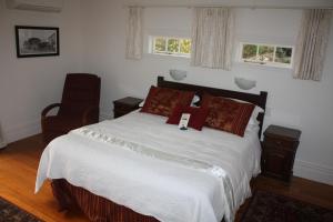 a bedroom with a bed and a chair and two windows at Paheke Boutique Lodge in Kaikohe
