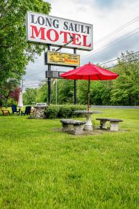 Long Sault Motel في Long Sault: طاولة نزهة مع مظلة حمراء بجوار موتيل