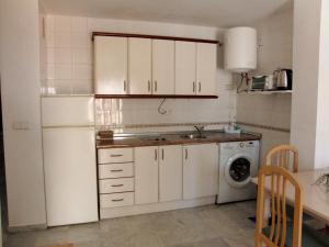 cocina con armarios blancos, fregadero y lavadora en Apartamento Junto a El Corte Inglés Algeciras 3, en Algeciras