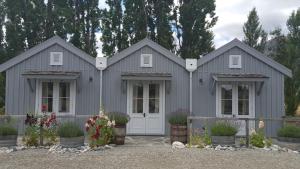 a gray house with flowers in front of it at Gibbston Boathouse with Outdoor Bath in Gibbston