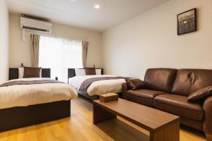 sala de estar con 2 camas y sofá en Cocolie BEPPU, en Beppu